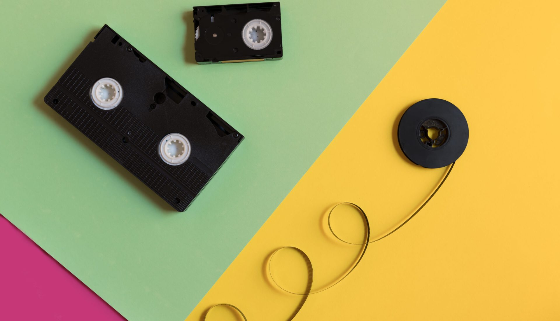 two types of old video cassettes and old film with copyspace on a pastel three-color paper background, minimalism, 1980s, 1970s, retro concept, top view